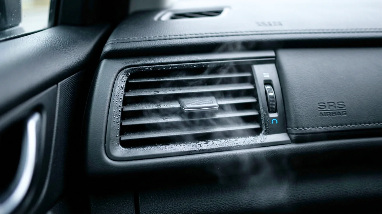 Car AC not blowing cold air illustrated by a dashboard air vent with condensation forming around it